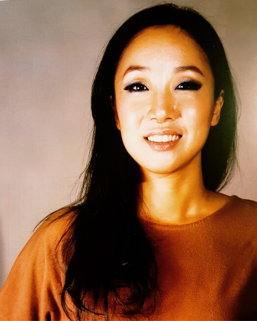 Actor Eunyoung Park smiling in a pumpkin colored shirt.