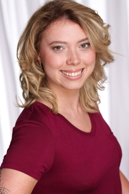 Actor Kristen Brimm smiling in a burgundy shirt.