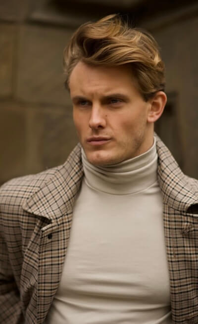 Actor Rockwell Nixon looking stoic in a plaid jacket.