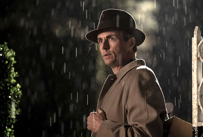 Actor Matthew Goode in a trench coat outside in the rain.