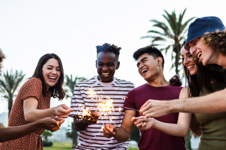 Diverse group of friends celebrating summer outside with sparklers.