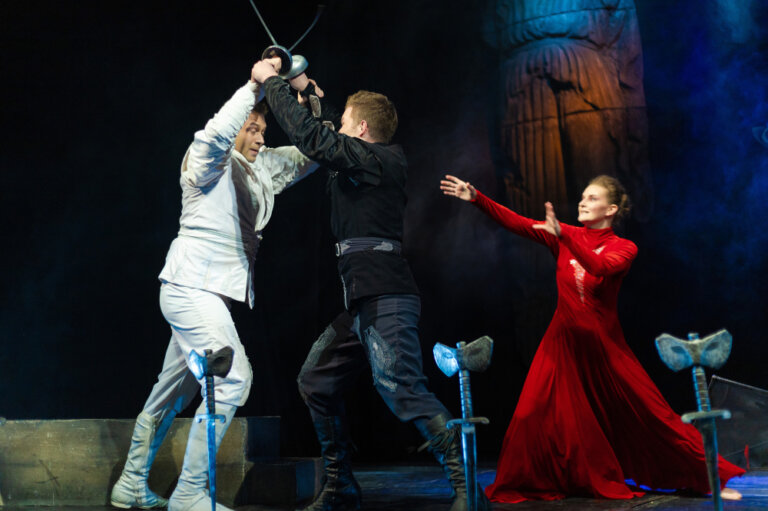 Shakespeare actors performing a sword fight scene in a play.