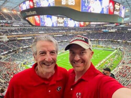 Chase Paris and a friend wearing red shirts at a football game.