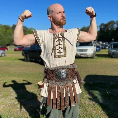 Chase Paris flexing at a Renaissance fair dressed as a medieval strongman.