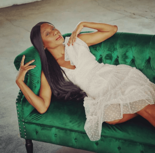 Actress Lana Leigh Taylor in a white dress on a green couch.