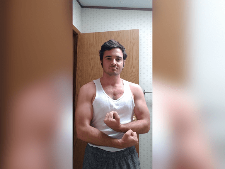 Actor Joseph Looper in shorts and a tank top flexing.