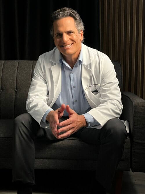 Darren Anselmo sitting down on the couch dressed as a doctor.