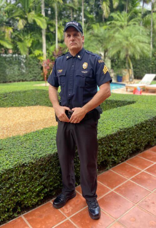 Darren Anselmo dressed as a police officer outside a building.