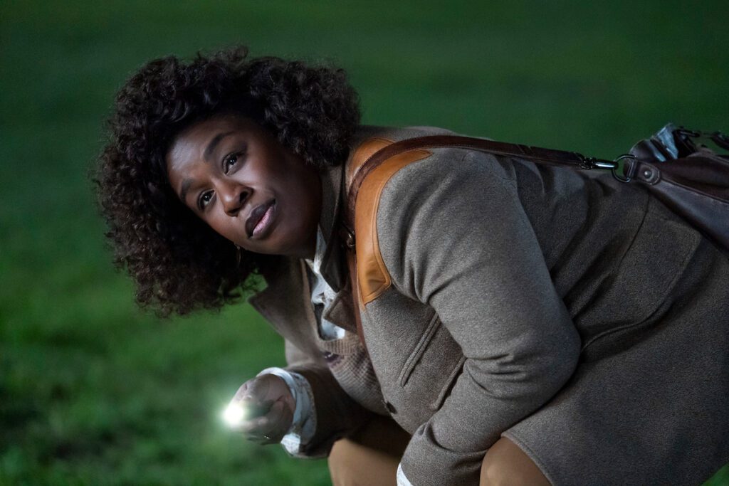 Uzo Aduba bending over on the grass inspecting a crime scene in Netflix's The Residence.