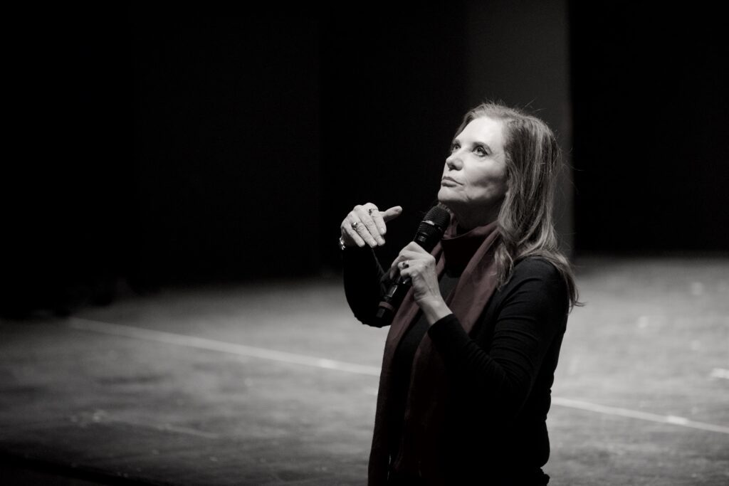 Acting teacher Ivana Chubbuck standing on a stage looking up. A black-and-white filter is applied.