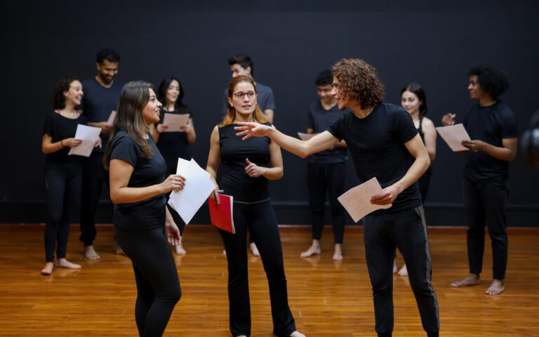 Latinx actors rehearsing a scene with an intimacy coordinator present, pink book in hand.