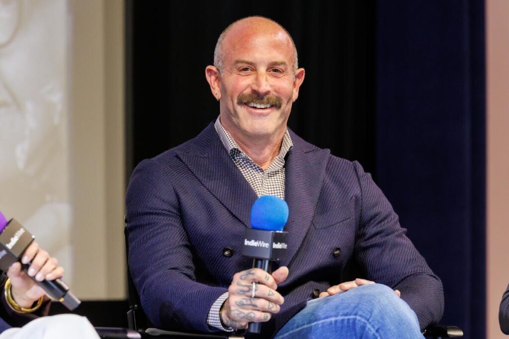 Casting director Seth Yanklewitz sitting in a chair wearing a blazer while speaking at a conference.