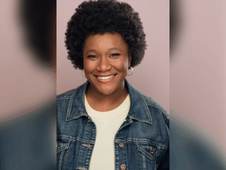 Actor Celine Milie smiling in front of a pink background wearing a blue denim jacket over a white shirt.